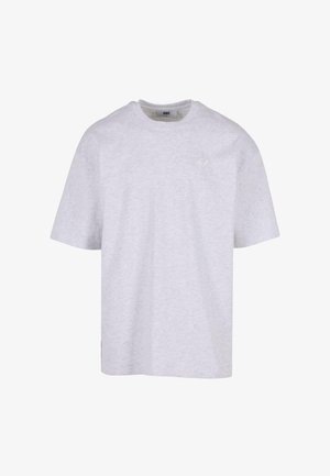 Camiseta de algodón gris, de manga corta, con cuello redondo, con un pequeño logo impreso en un tono más claro en el pecho. Diseño simple, sin patrones.