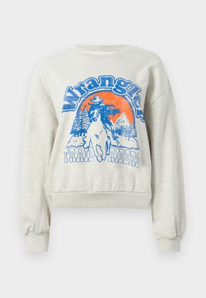 Sweatshirt gris clair avec un col rond et des poignets côtelés. Présente un graphic bleu et orange d'un cowboy à cheval avec des arbres.