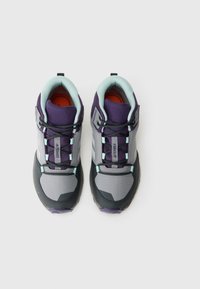 Un paio di scarpe da ginnastica grigie e viola con lacci neri e accenti blu chiaro, viste dall'alto su uno sfondo bianco.
