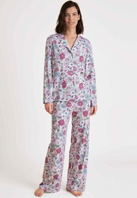 Floral pyjama set met een knoopsluiting, lange mouwen top en bijpassende losse broek, in pastelkleuren met een levendig bloemenpatroon op zachte stof.