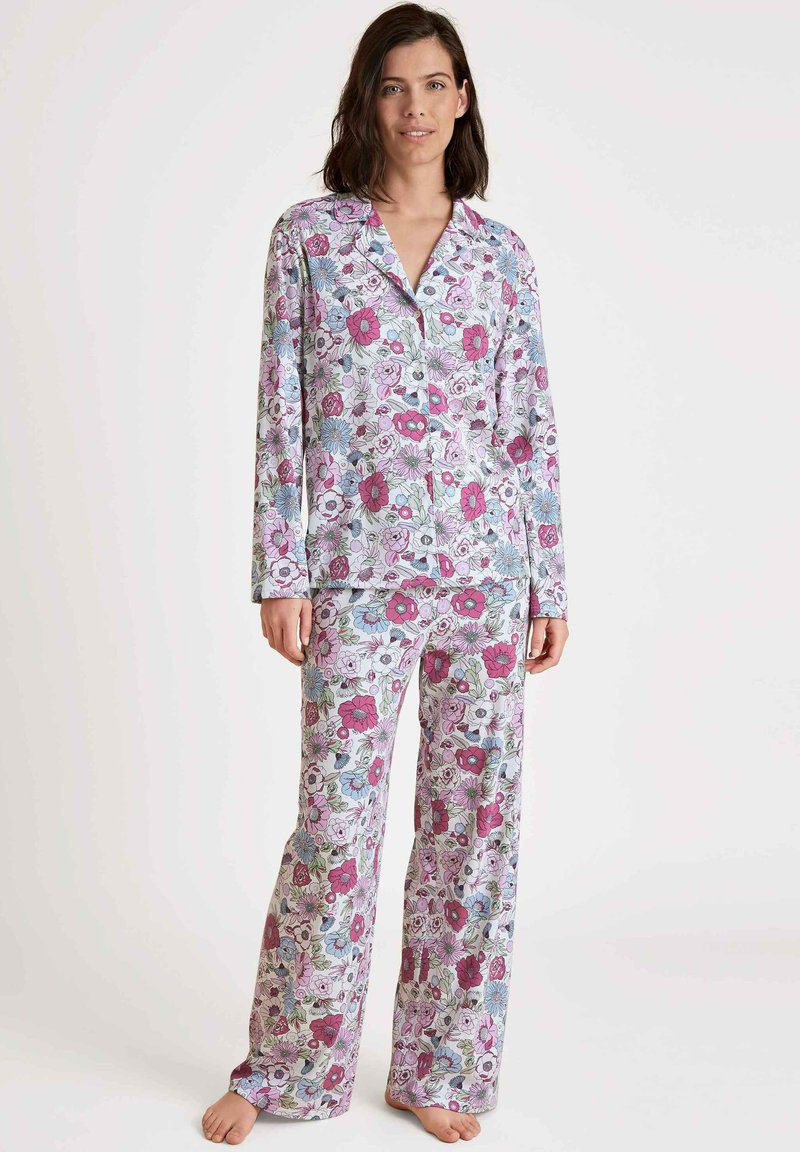 Floral pyjama set met een knoopsluiting, lange mouwen top en bijpassende losse broek, in pastelkleuren met een levendig bloemenpatroon op zachte stof.