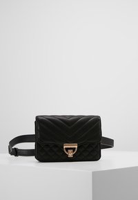 Borsa a tracolla nera trapuntata con motivo a zig zag, hardware dorato e una tracolla. Design compatto con chiusura a pattina e forma squadrata.