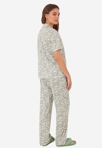 Ensemble de vêtements de détente à imprimé floral en vert et blanc, comprenant des manches courtes et un pantalon ample. Inclut des sandales glissantes vert clair.