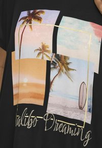 Camiseta negra con un diseño gráfico que presenta imágenes de playa y palmeras en colores pastel, contorneadas en dorado, con el texto "Malibu Dreaming."