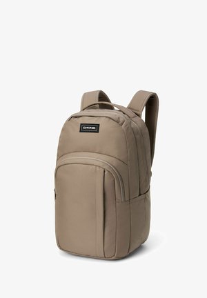 Dakine reppu beige-kankaasta, jossa on pääosasto, etutasku vetoketjulla, pehmustetut olkahihnat ja logopatchi edessä.