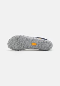 Suela de zapato con una superficie de goma gris texturizada, que presenta un patrón de panal y un logo amarillo, diseñada para ofrecer tracción y durabilidad.