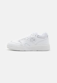 Fehér sportcipő, sima bőr felsőrésszel, hálós elemekkel, fűzős záródással és texturált gumi talppal. Lacoste logó az oldalon.