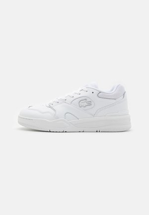 Valkoiset urheilukengät, joissa on sileä nahkapinta, verkko-osiot, nauhakiinnitys ja teksturoitu kumipohja. Lacoste-logo sivussa.