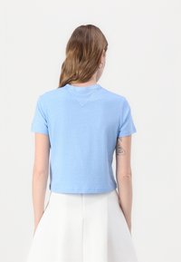 T-shirt azzurro chiaro a maniche corte realizzato in morbido cotone, con scollo rotondo e un design corto che presenta un dettaglio a V cucito sul retro.
