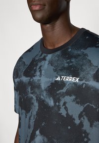 Must mustriga T-särk musta ja tumeda sinise mustriga, ümmarguse kaelusega. Rinnal on valge "TERREX" logo. Pehme tekstuuriga kangas.