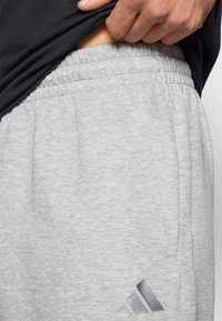Grå sweatpants tillverkade av mjukt tyg med en samlad elastisk midja. Har en diskret logotyp i en mörkare nyans på underbenet.