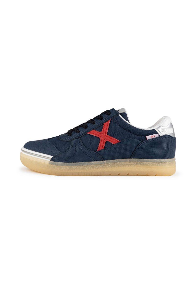 Zapatillas de lona azul marino con un logo 'X' bordado en rojo, cordones negros y suela de goma. Detalles plateados en el talón.