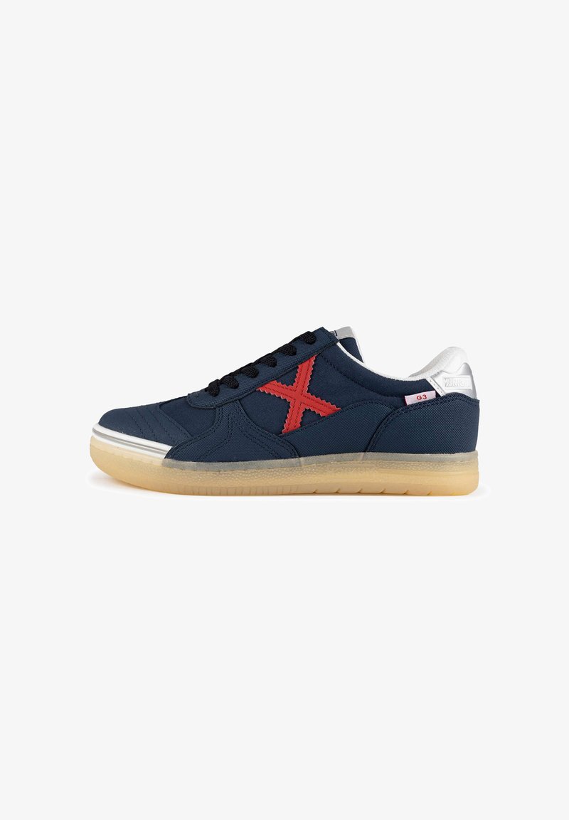 Zapatillas de lona azul marino con un logo 'X' bordado en rojo, cordones negros y suela de goma. Detalles plateados en el talón.