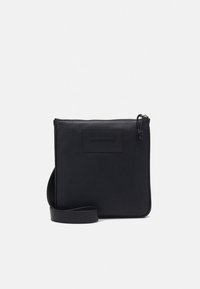 Borsa a tracolla in pelle nera con texture liscia, forma quadrata, chiusura con zip e una toppa piatta in pelle sulla parte anteriore.