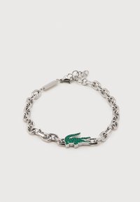 Ασημένιο βραχιόλι αλυσίδα με πράσινο χάντρα σε σχήμα κροκόδειλου και κούμπωμα με κλαμπόν, πάνω σε λευκό φόντο.