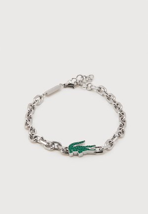 Silver chain bracelet with a green rhinestone crocodile charm and lobster clasp on a white background.
