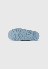 Semelle de chaussure bleu clair avec un motif géométrique texturé et le nom de la marque "UGG" embossé au centre.