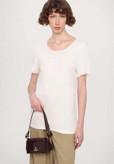 Cream short-sleeve top with a round neckline, paired with beige trousers and a small burgundy handbag featuring an anchor logo.