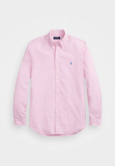 Camisa de botão rosa claro com riscas verticais brancas e um pequeno logótipo azul no lado esquerdo do peito. Apresenta colarinho e mangas longas.