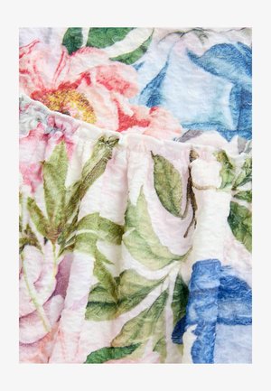 Kvetinová látka s veľkými ružovými a modrými kvetmi a zelenými listami. Textúrované biele pozadie so zhládanými okrajmi a jemnými, živými farbami.