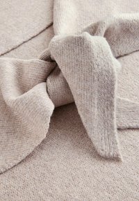 Bežikirju kangas tekstureeritud viimistlusega, millel on suur kangast lipsu detail, mis katab materjali. Pehme ja mugav välimus.