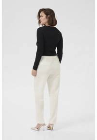 Zwarte lange mouwen top, slim fit ontwerp; gecombineerd met witte broek, rechte snit; zilveren hakken, gladde textuur. Minimalistische stijl.