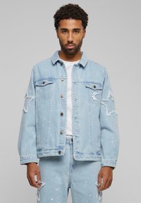 Light blue denim jacket featuring a distressed design, star patches on the sleeves, and contrasting paint splatter details.