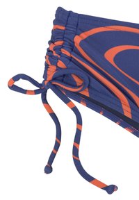 Bikini onderkant in blauw met een oranje spiraalpatroon. Beschikt over gathering aan de zijkanten en verstelbare touwtjes voor een aangepaste pasvorm. Gemaakt van rekbaar materiaal.