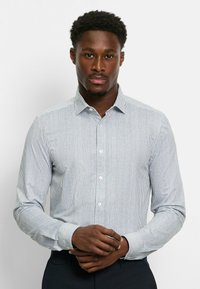 Weiß- und blau gestreiftes Langarmhemd mit spitzem Kragen, Knopfleiste und geknöpften Ärmeln, aus leichtem Stoff gefertigt.