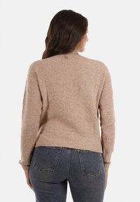 Maglione a coste color khaki con maniche lunghe e scollatura rotonda, caratterizzato da un piccolo logo sul retro e un orlo dritto.