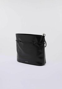 Borsa a tracolla rettangolare in pelle nera con un semplice dettaglio in corda e anello in metallo argentato sulla tracolla, su uno sfondo bianco semplice.