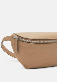 Braune Leder-Bauchtasche mit glatter Textur, gewölbter Form, vorderem Reißverschluss und Seitengriff. Mit geprägtem Logo an der Unterseite.