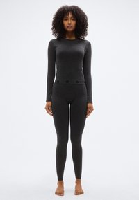 Μακρυμάνικη μπλούζα σκούρου γκρι χρώματος και αντίστοιχο κολάν από μαλακό, ελαστικό ύφασμα· διαθέτουν διακοσμητική μέση με λεπτό σχέδιο.