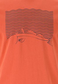 Orange bomull t-shirt med en svart grafik av en fisk och vågiga linjer ovanför den, vilket skapar en enkel, tydlig design.