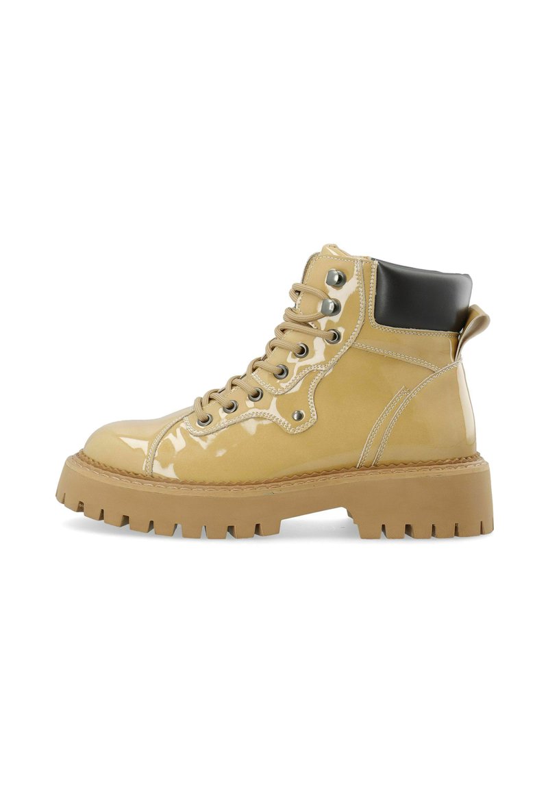 Bottines à lacets en cuir verni jaune clair brillant avec un accent de talon noir, une semelle en caoutchouc épaisse et des détails en métal argenté.