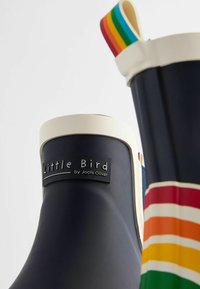 Stivali da pioggia in gomma blu navy con suole bianche e un manico colorato a strisce. Presentano un'etichetta nera con la scritta "Little Bird by Jools Oliver."