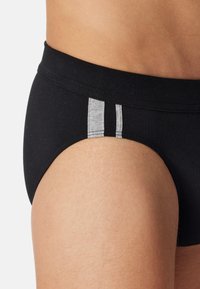 Sorte briefs med en blød elastik og to lodrette grå striber på siden. Fremstillet af et glat stof med en tætsiddende design.
