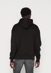Schwarzer Hoodie mit großzügigem Design, langen Ärmeln und einer großen, weichen Kapuze. Hergestellt aus einem bequemen Stoff mit gerippten Bündchen und Saum.