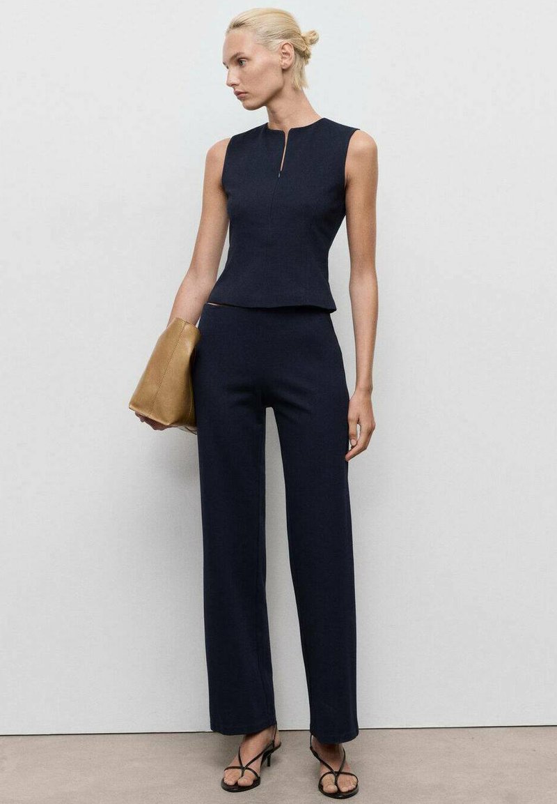 Námořnický dvoudílný outfit se bezrukávovým topem s peplum a kalhotami širokého střihu, vyrobený z texturované tkaniny. Doplněno béžovou kabelkou.