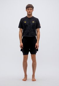 Μαύρο αθλητικό σύνολο που αποτελείται από ένα κοντομάνικο τοπ με υφασμάτινη σχεδίαση και λογότυπα, σε συνδυασμό με αντίστοιχο σορτς.