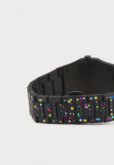 Sort ur med et farverigt, plettet silikonebånd, der har varierende størrelser af prikker i pink, blå, grøn og gul fordelt over kæderne.