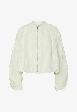 Lyhyt takki vaaleasta kerma-kankaasta, jonka pinnassa on monimutkainen valkoinen kukkakirjonta, korkea kaulus ja edessä vetoketju. Valtavat hihat.