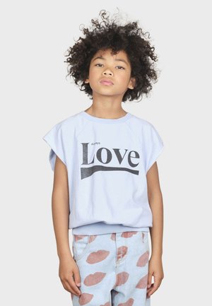 T-shirt à manches courtes bleu clair avec "Always Love" écrit en gras en noir. Associé à un pantalon en denim clair avec des motifs de lèvres roses.