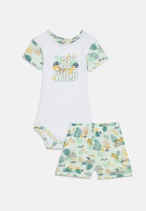 Body bianco per neonati con testo "BE WILD" e maniche corte a tema giungla in tonalità pastello, e pantaloncini abbinati con stampe di animali e foglie.