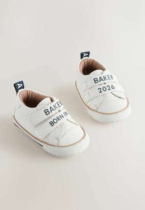 Białe sneakersy dla niemowląt z ekologicznej skóry, zapinane na dwa paski Velcro. Posiadają napisy "BAKER" i "BORN IN", teksturowaną gumową podeszwę oraz brązowe wykończenie.