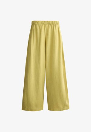 Ohlapne, široke hlače v gorčično rumeni barvi z elastiko v pasu, prikazane na belem ozadju.