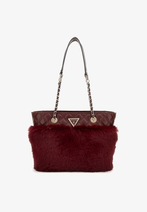 Viininpunainen tikattu käsilaukku kultaisilla ketjuhihnoilla ja etuosassa keinoturkispaneeli, jossa on kolmionmuotoinen Guess-logo.