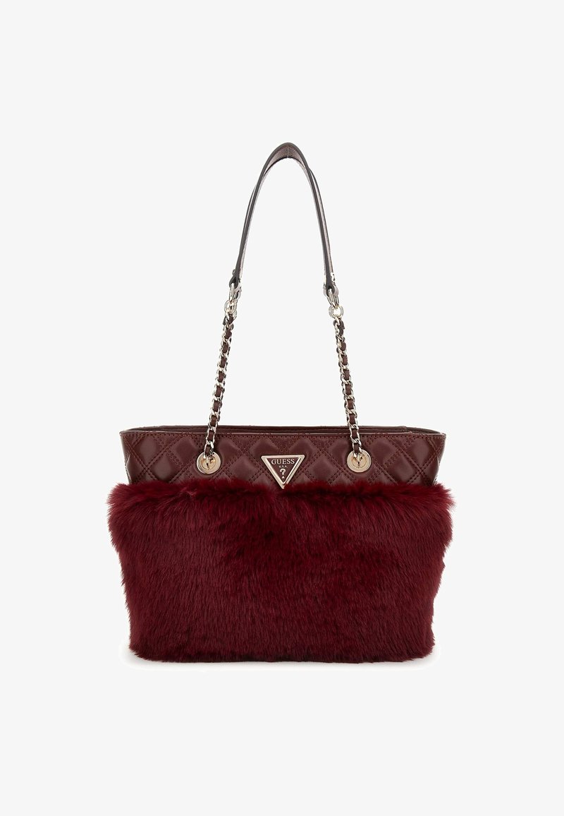 Sac à main matelassé bordeaux avec des anses en chaîne dorée et un panneau en fausse fourrure sur le devant, arborant un badge logo triangulaire Guess.