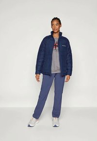 Σακάκι ναυτικού χρώματος με απο insulation και ψηλό γιακά, σε συνδυασμό με γκρι μπλούζα και μπλε παντελόνι. Περιλαμβάνει κεντητή υφή και λεπτομέρεια λογότυπου στο στήθος.