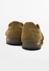 Chaussures en daim marron à profil bas, bout rond et semelle en caoutchouc. Présentent une couture minimale pour un design épuré.
